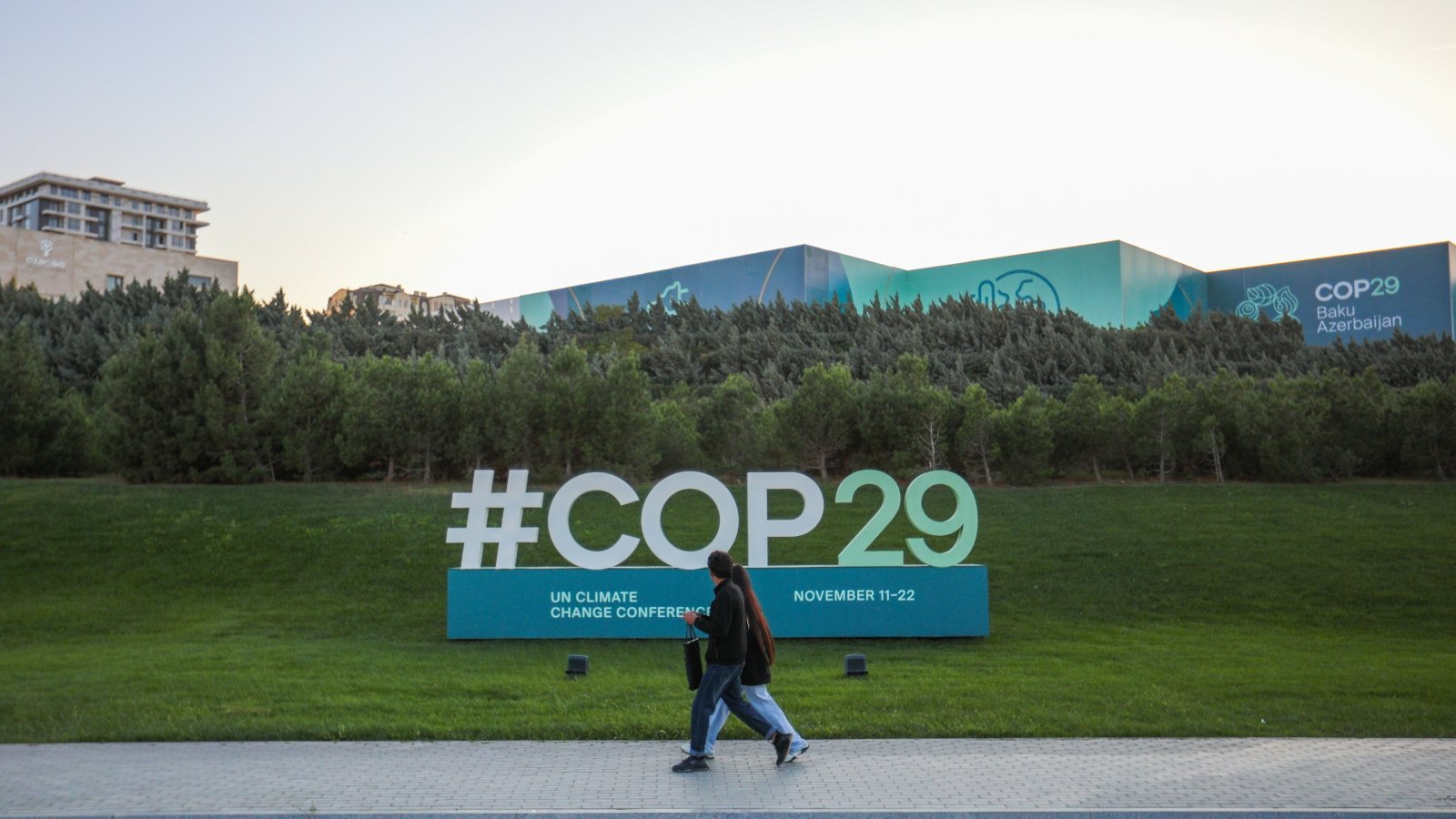 مواطنون يمشون بالقرب⁤ من علامة COP29 قرب ملعب باكو الأولمبي ،⁢ مكان انعقاد مؤتمر الأمم المتحدة لتغير المناخ‌ COP29 بتاريخ 23 أكتوبر 2024.